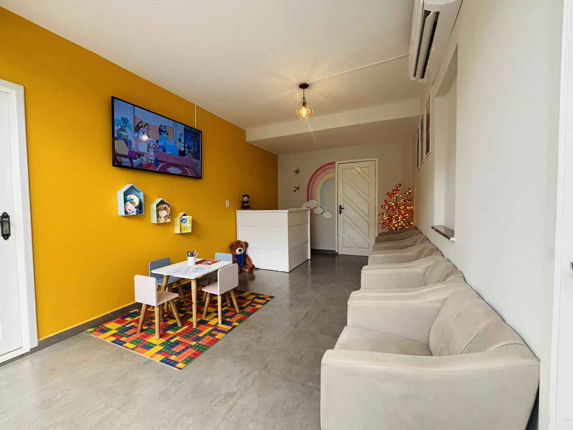 Recepção da Clínica Infantástica com decoração amarela vibrante e ambiente acolhedor para crianças